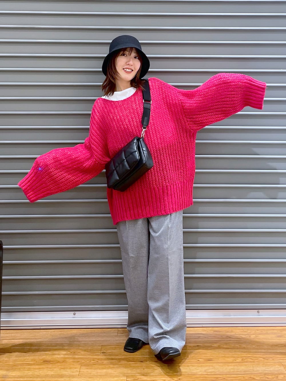 ピンク系のニット/セーター、ブラック系のショルダーバッグ、ホワイト系のTシャツ/カットソーを着用したレディースの秋コーディネートの2枚目の写真