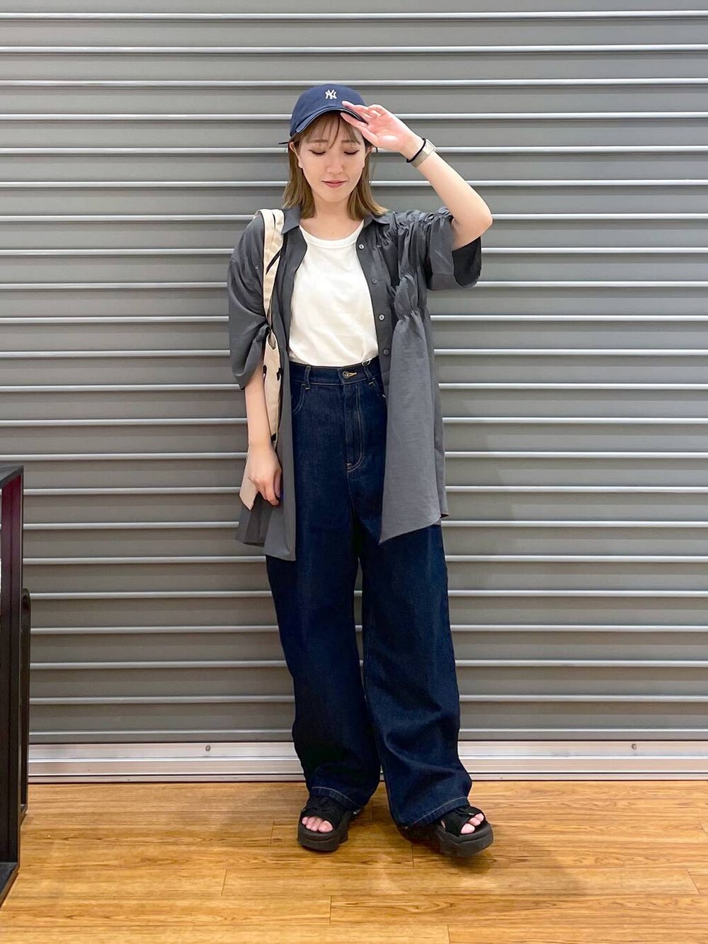 グレー系のシャツ/ブラウス、ブラウン系のトートバッグ、ブルー系のデニムパンツを着用したレディースの夏コーディネートの2枚目の写真