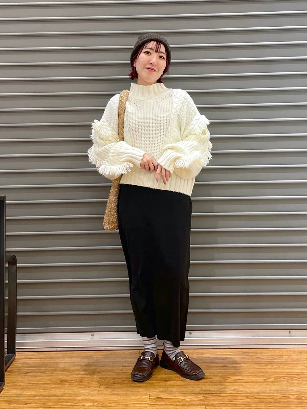 ブラック系のスカート、ゴールド系のショルダーバッグ、ホワイト系のニット/セーターを着用したレディースの冬コーディネートの2枚目の写真