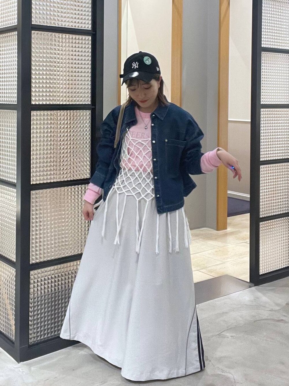 ピンク系のTシャツ/カットソー、ホワイト系のベスト、ベージュ系のショルダーバッグを着用したレディースの春コーディネートの2枚目の写真