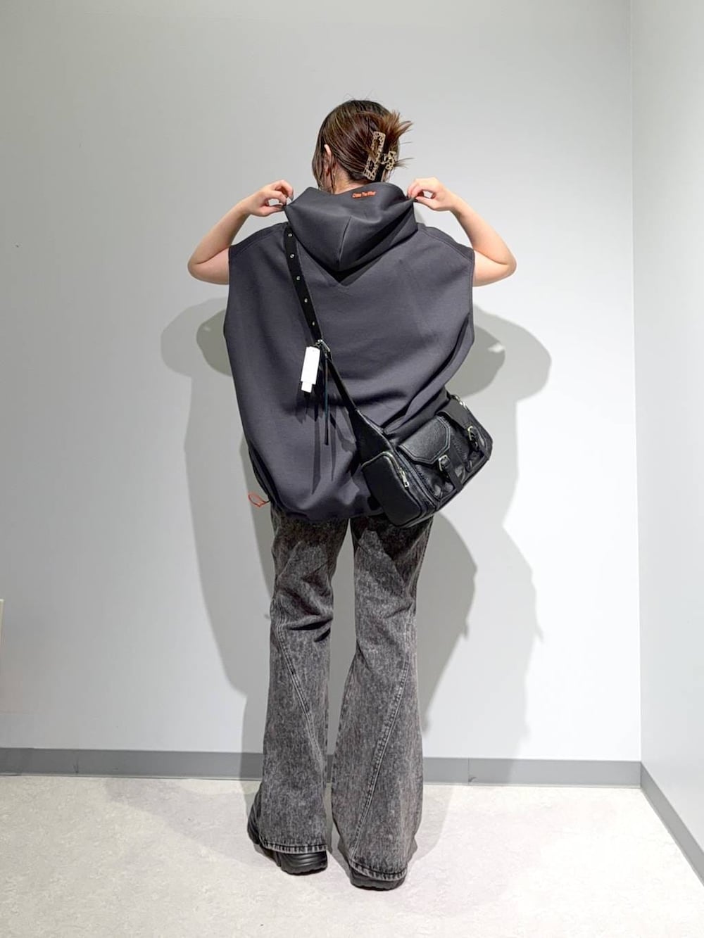 グレー系のベスト、ブラック系のデニムパンツ、ブラック系のショルダーバッグを着用したレディースの夏コーディネートの3枚目の写真