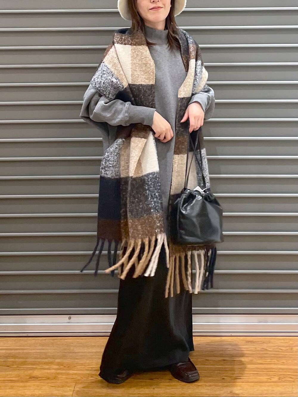 グレー系のチュニック、ブラック系のスカート、ブラック系のショルダーバッグを着用したレディースの冬コーディネートの3枚目の写真