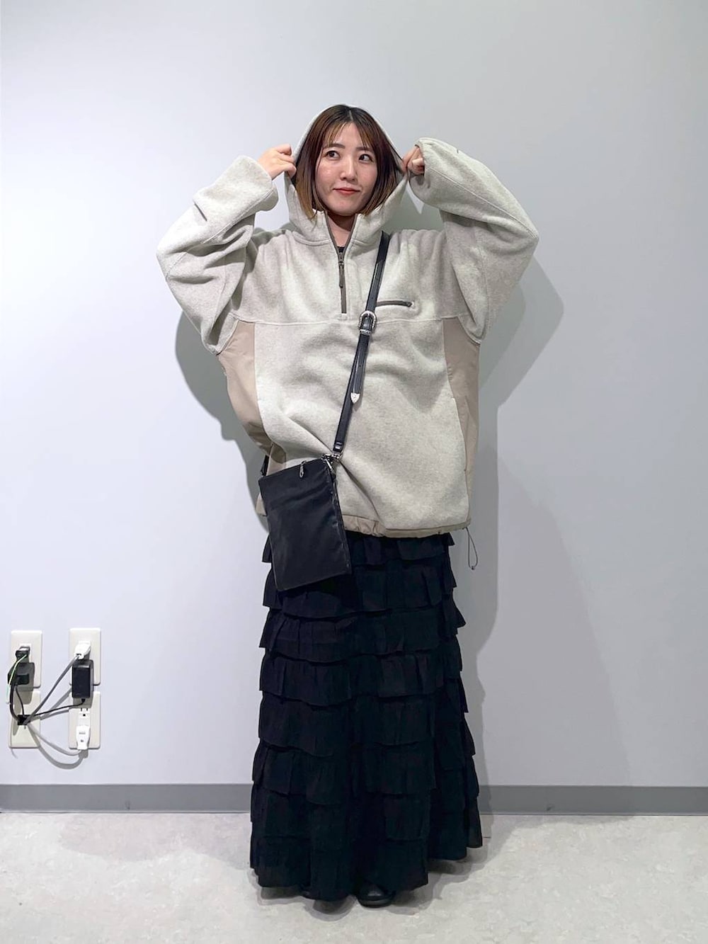 ブラック系のスカート、ブラック系のショルダーバッグ、ベージュ系のパーカーを着用したレディースの秋コーディネートの2枚目の写真