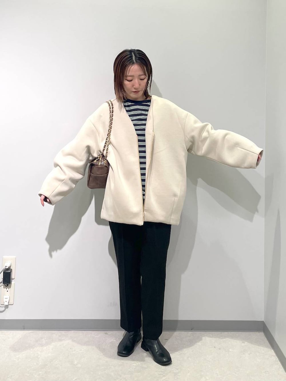 ホワイト系のブルゾン、ブラック系のスラックス、ブラウン系のショルダーバッグを着用したレディースの春コーディネートの3枚目の写真