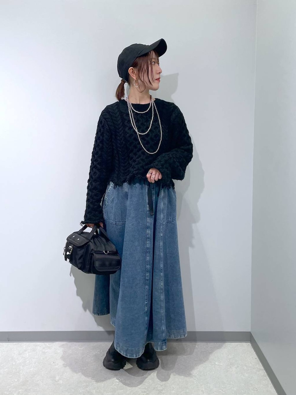 ブラック系のスカート、ブラック系のボストンバッグ、ブラック系のキャップを着用したレディースの冬コーディネートの2枚目の写真