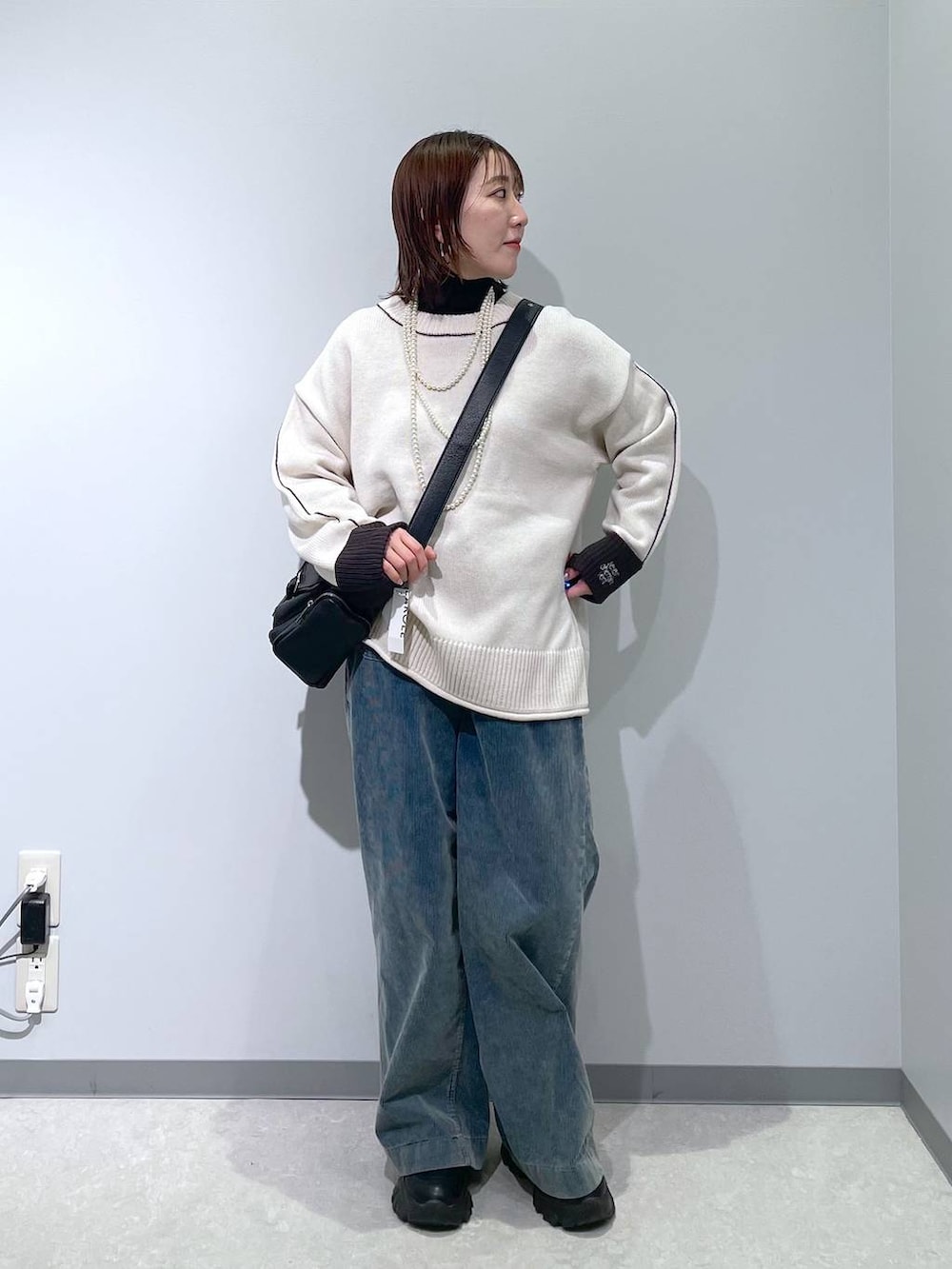 ブラック系のニット/セーター、ブルー系のその他パンツ、ブラック系のショルダーバッグを着用したレディースの冬コーディネートの2枚目の写真