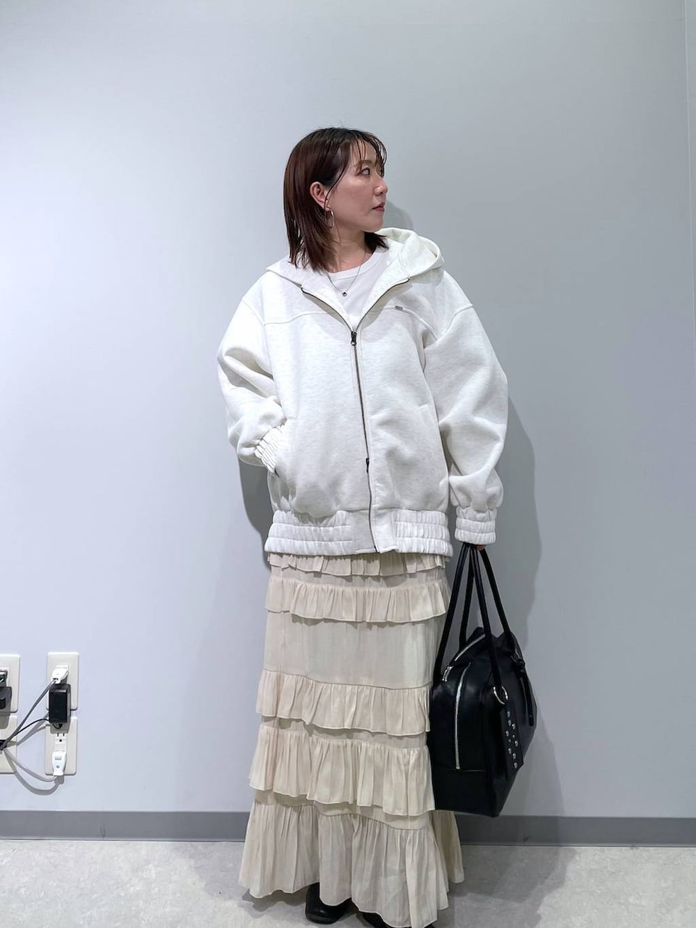 ブラック系のボストンバッグ、ベージュ系のブルゾン、ホワイト系のスカートを着用したレディースの春コーディネートの3枚目の写真