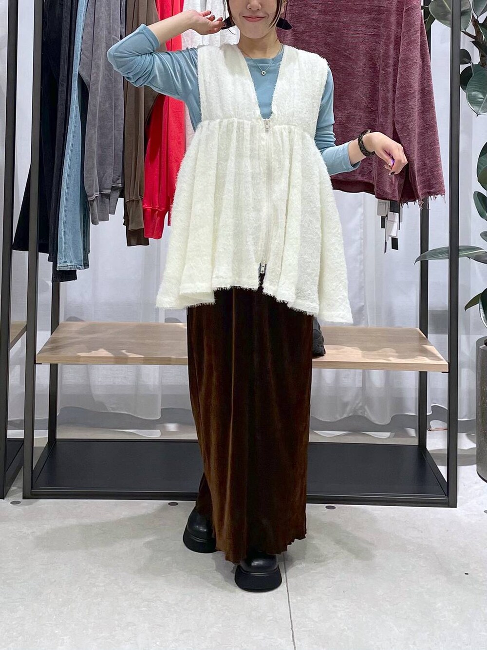 ホワイト系のベスト、ブラウン系のスカート、ブラック系のサンダルを着用したレディースの秋コーディネートの2枚目の写真