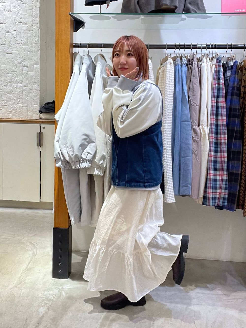 ホワイト系のスカート、ブルー系のベスト、グレー系のジャージを着用したレディースの春コーディネートの3枚目の写真