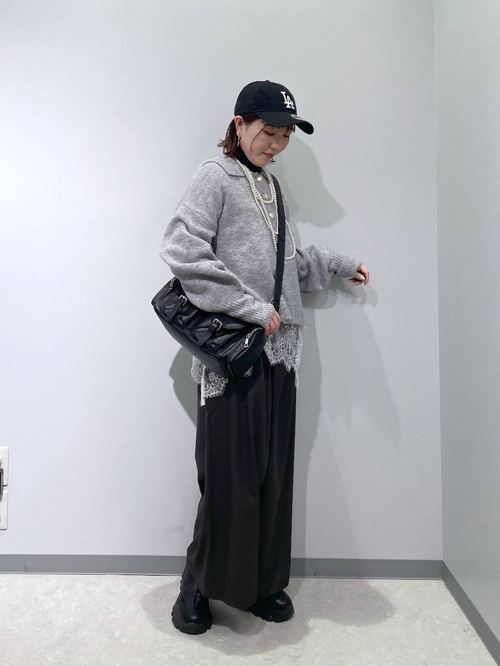 ブラック系のニット/セーター、グレー系のその他パンツ、ホワイト系のTシャツ/カットソーを着用したレディースの冬コーディネートの2枚目の写真