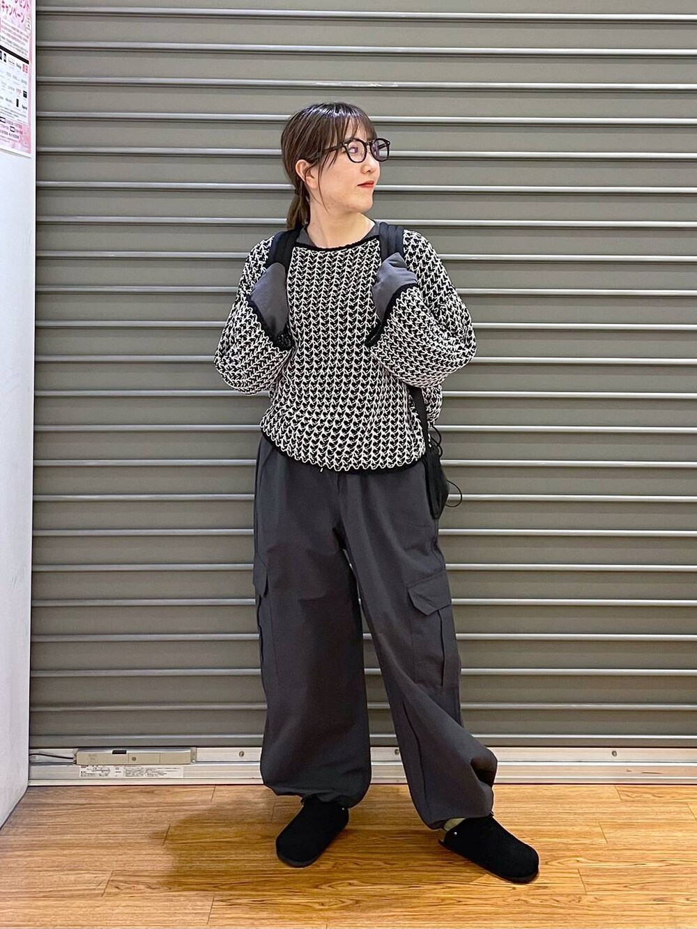 ブラック系のニット/セーター、グレー系のカーゴパンツ、ブラック系のバックパック/リュックを着用したレディースの春コーディネートの2枚目の写真