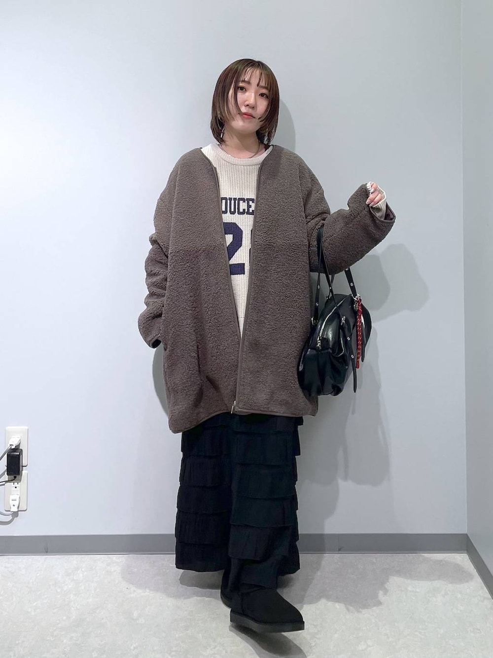 ブラック系のスカート、ブラウン系のその他アウター、ブラック系のブーツを着用したレディースの冬コーディネートの4枚目の写真