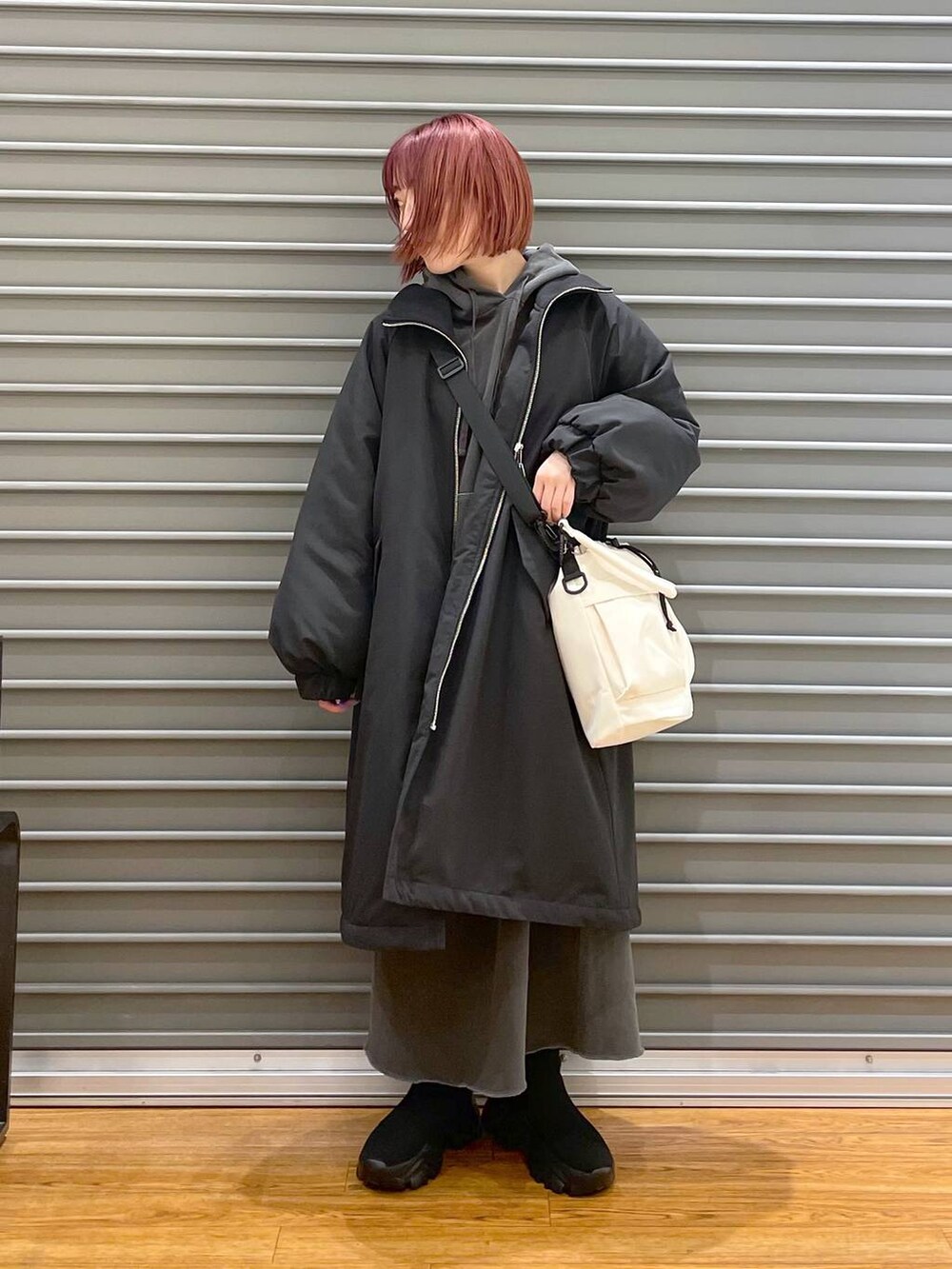 ブラック系のその他アウター、ブラック系のブーツ、ホワイト系のショルダーバッグを着用したレディースの冬コーディネートの2枚目の写真