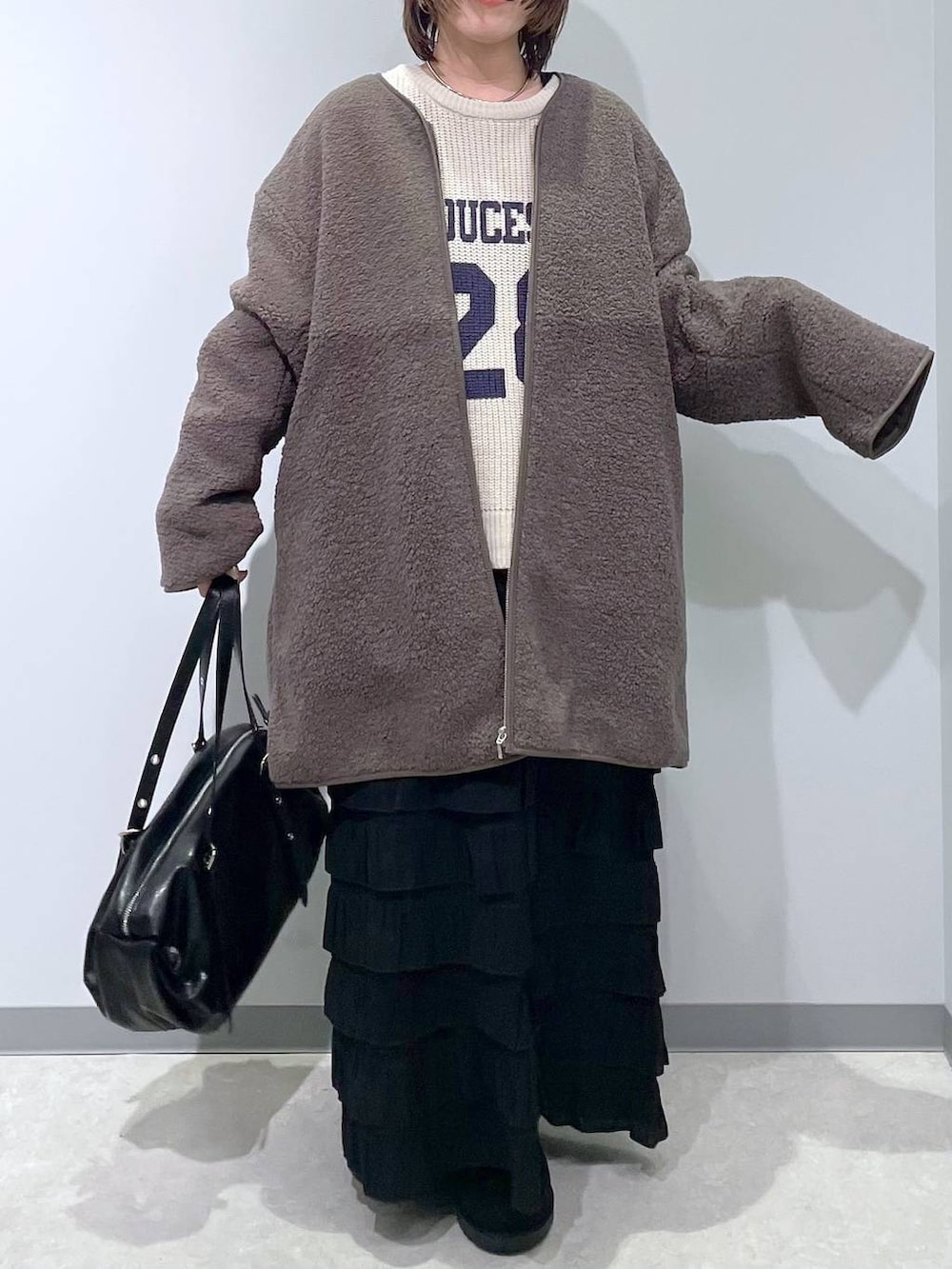 ブラック系のスカート、ブラウン系のその他アウター、ブラック系のブーツを着用したレディースの冬コーディネートの2枚目の写真