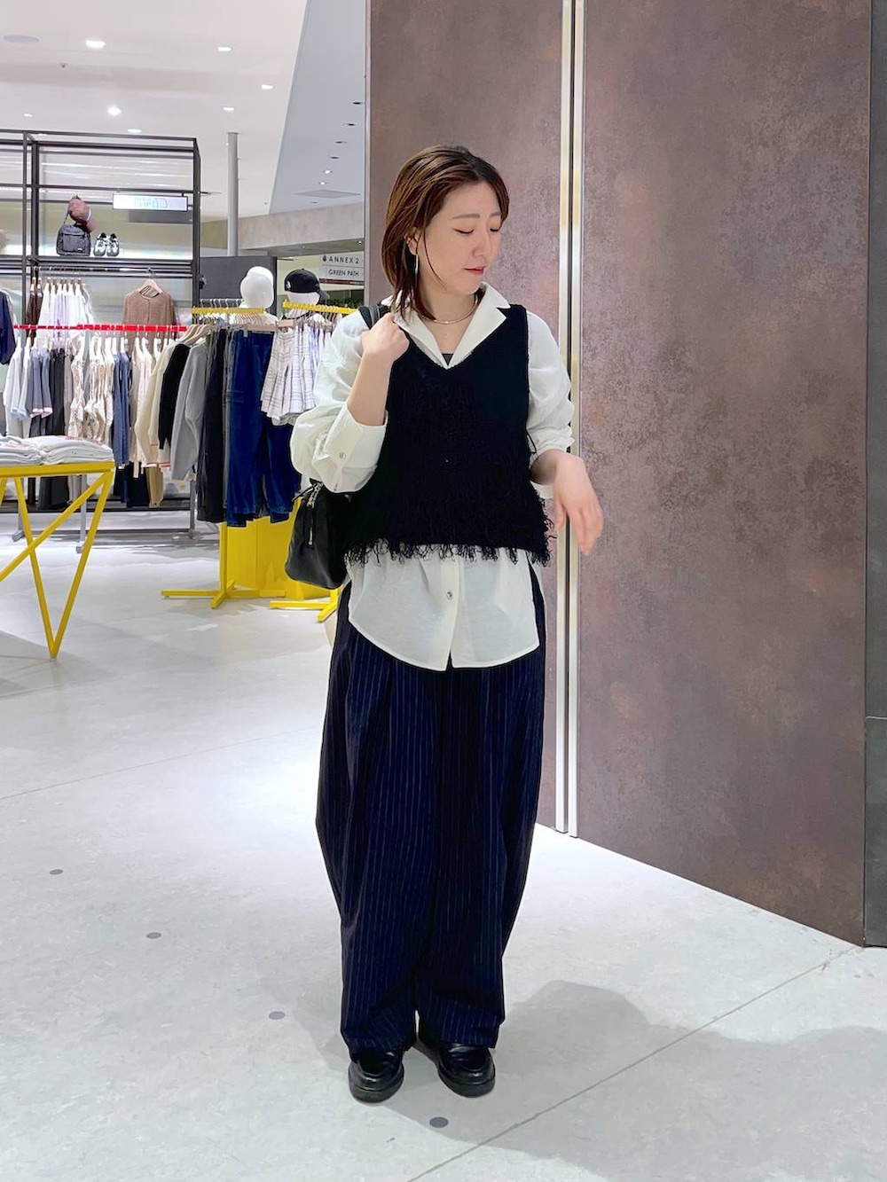 ブラック系のショルダーバッグ、ホワイト系のシャツ/ブラウス、ブラック系のベストを着用したレディースの春コーディネートの2枚目の写真