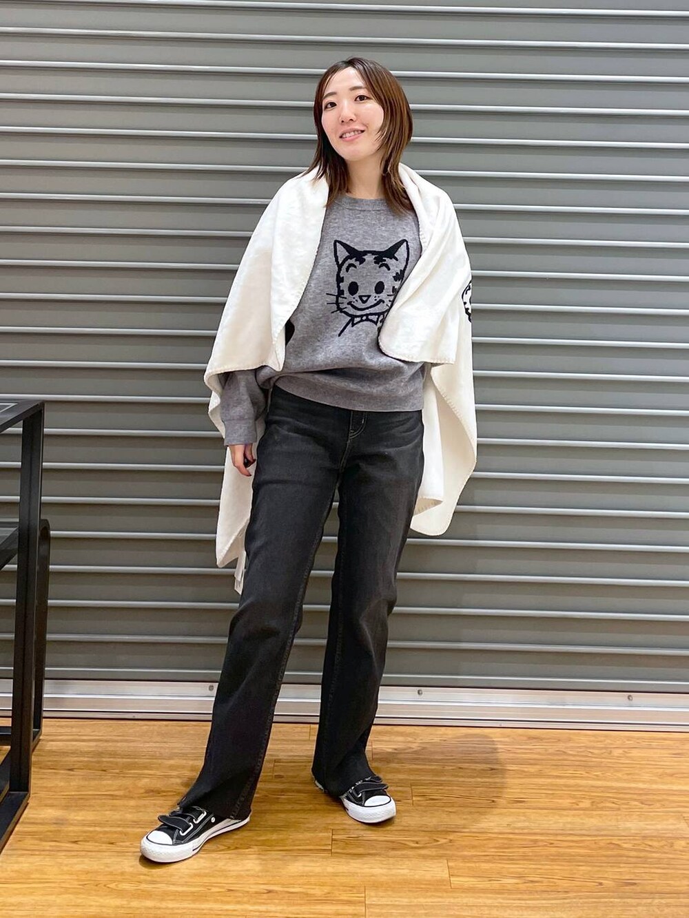 ブラック系のデニムパンツ、グレー系のニット/セーター、ホワイト系のブランケットを着用したレディースの冬コーディネートの3枚目の写真