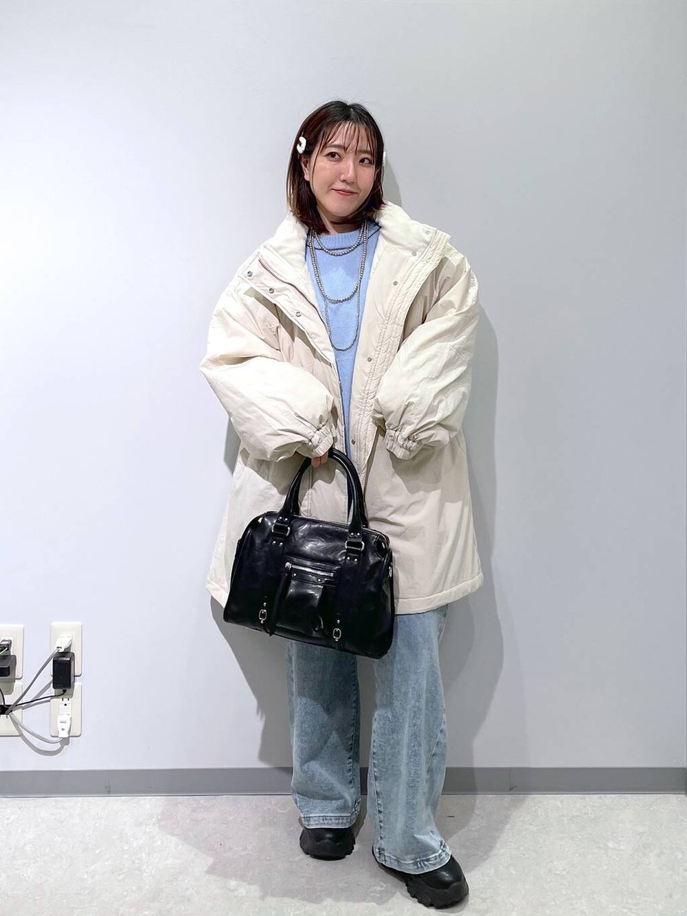 ホワイト系のブルゾン、ブラック系のボストンバッグ、ブルー系のデニムパンツを着用したレディースの冬コーディネートの4枚目の写真