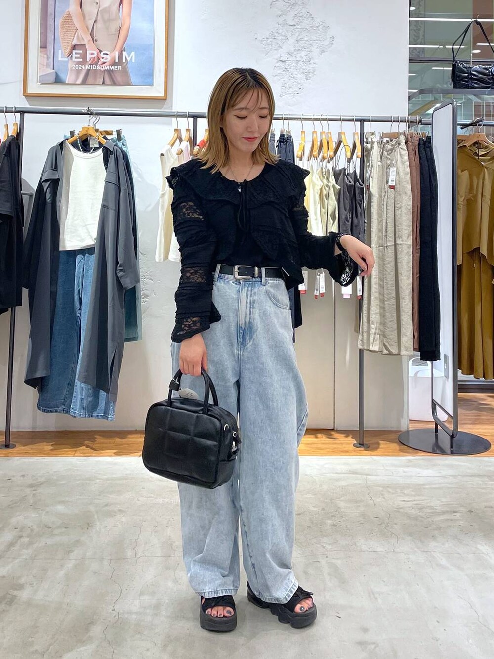 ブルー系のデニムパンツ、ブラック系のカーディガン/ボレロ、ブラック系のベルトを着用したレディースの夏コーディネートの3枚目の写真