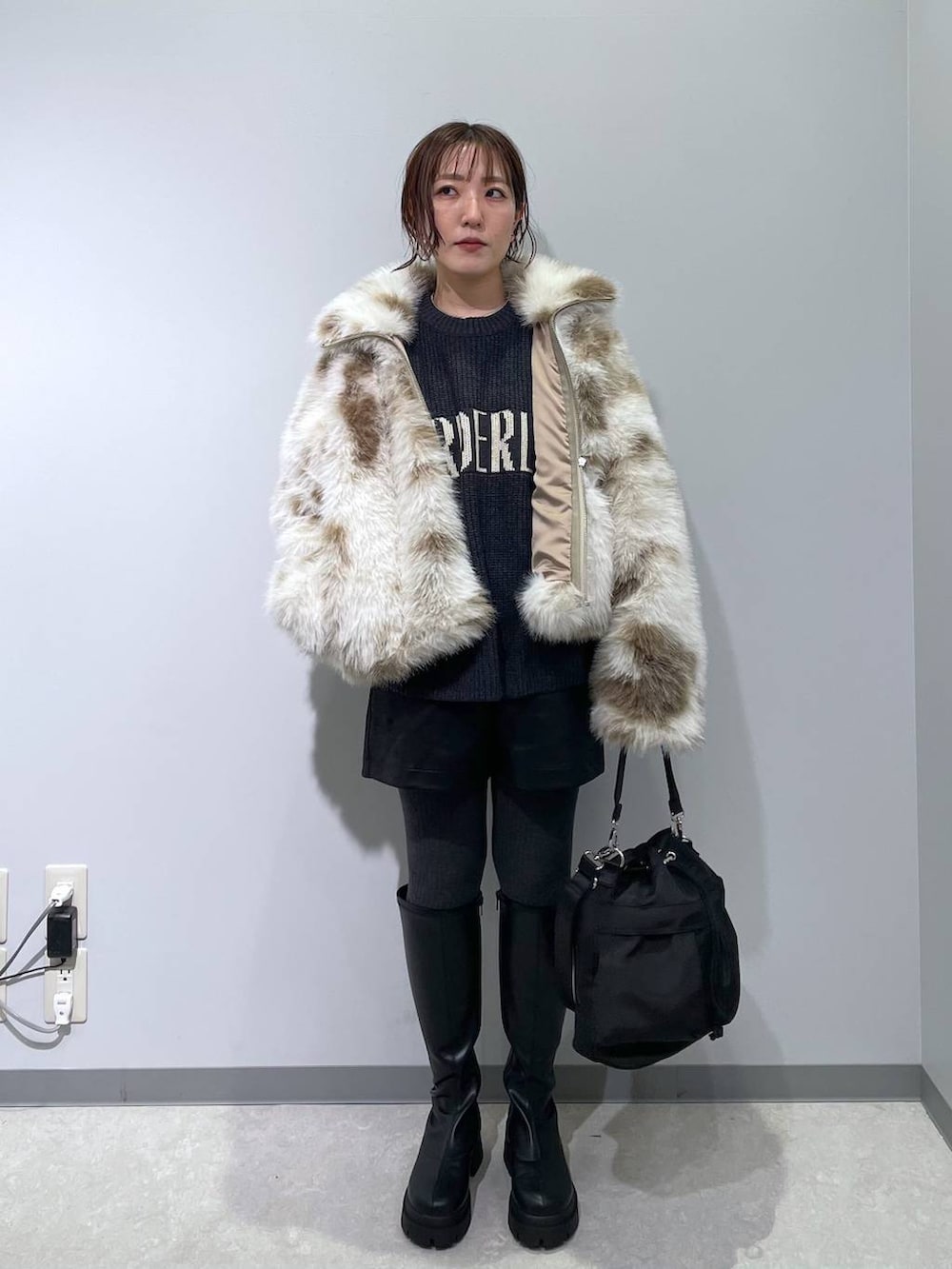 ホワイト系のブルゾン、ブラック系のショルダーバッグ、ブラック系のブーツを着用したレディースの冬コーディネートの2枚目の写真