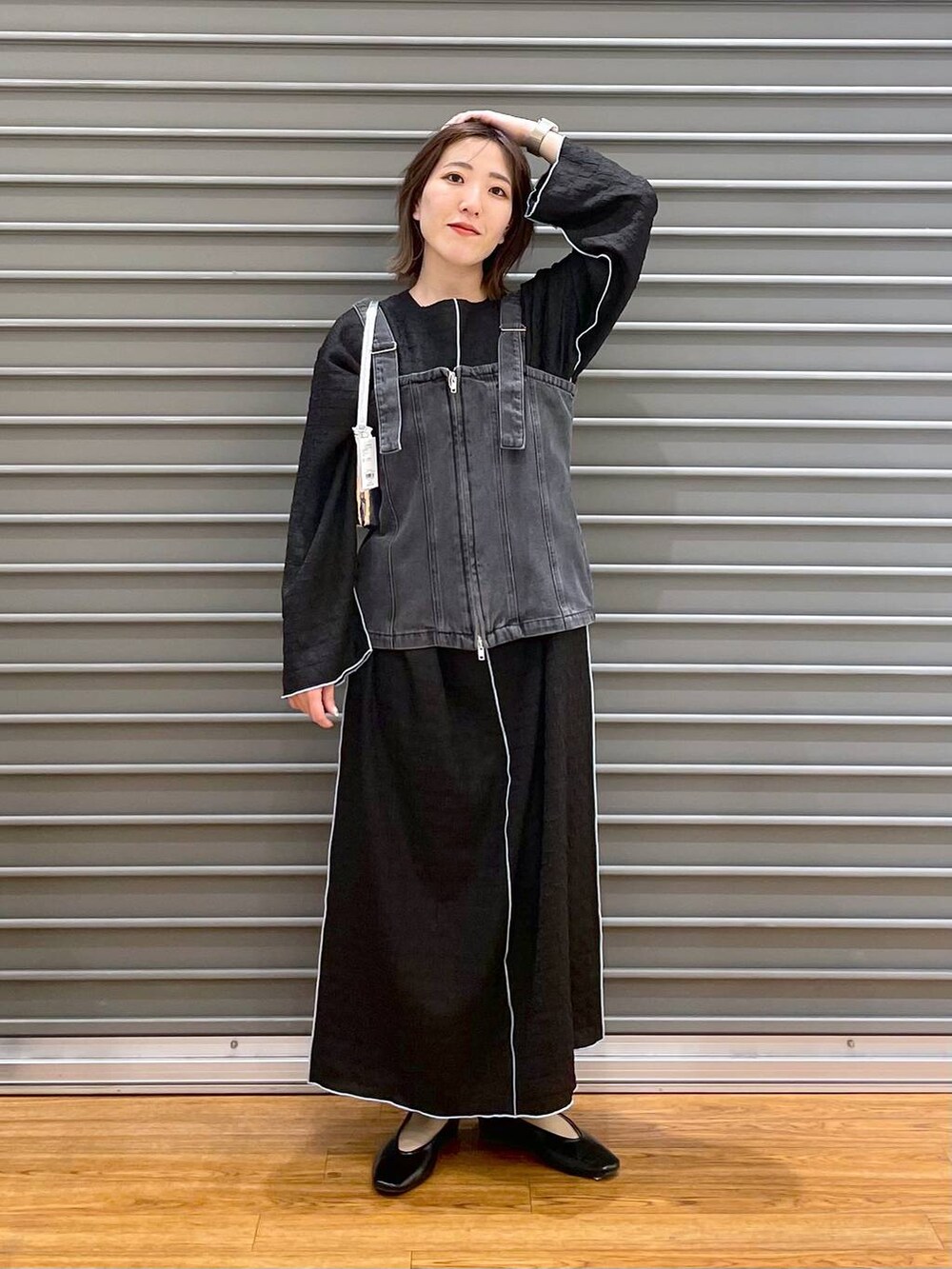 シルバー系のハンドバッグ、ブラック系のパンプス、ブラック系のベストを着用したレディースの春コーディネートの2枚目の写真