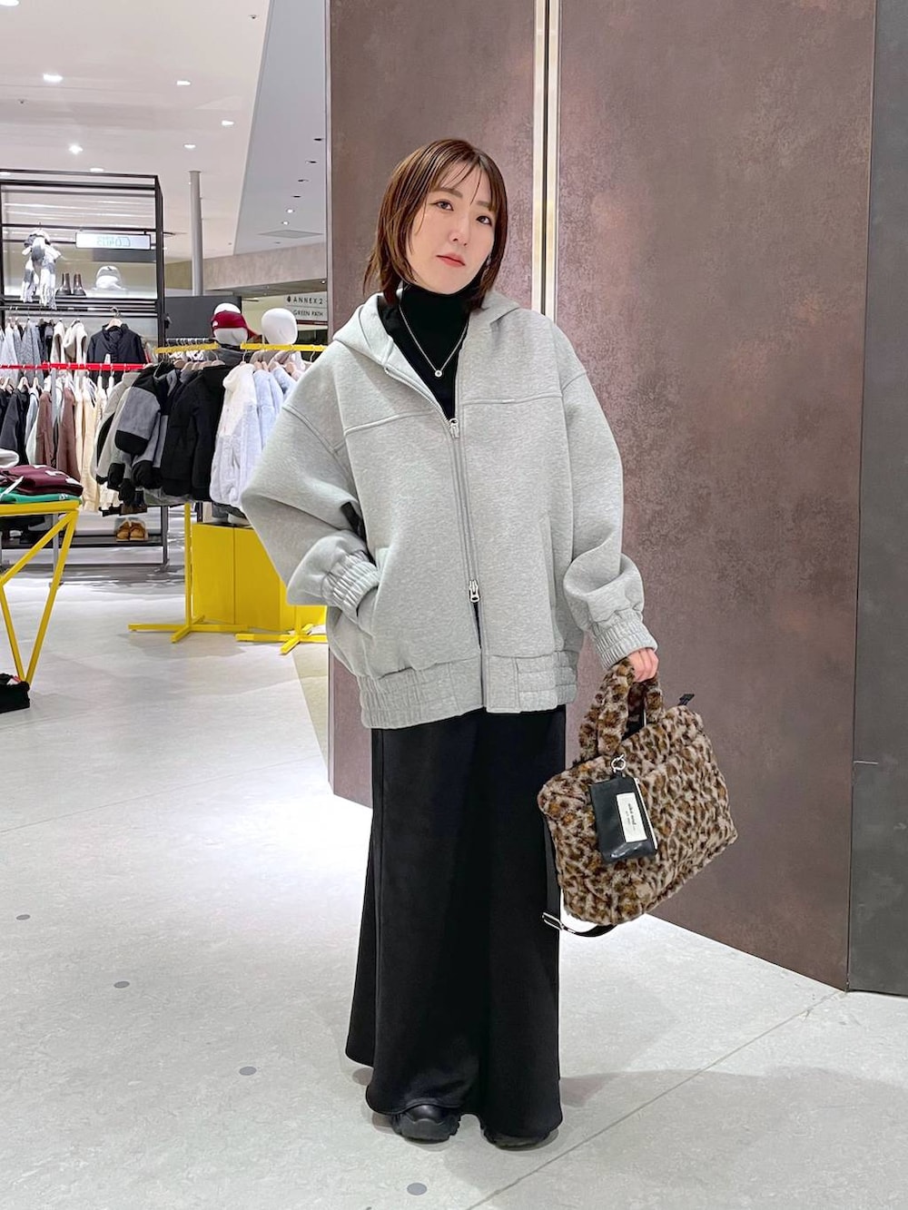 ブラック系のスカート、ブラック系のニット/セーター、グレー系のパーカーを着用したレディースの冬コーディネートの2枚目の写真