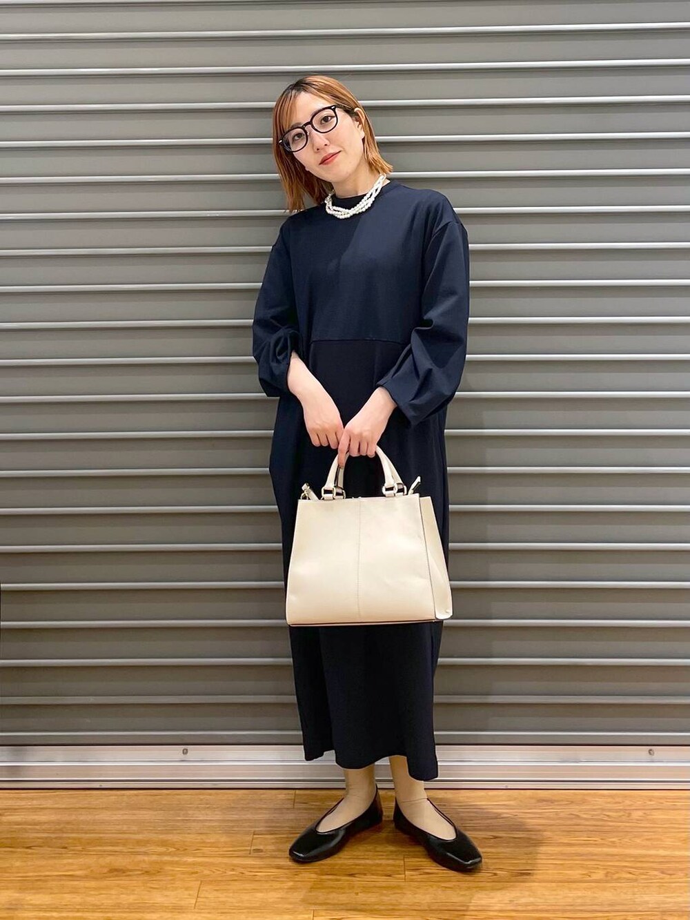 ブラック系のパンプス、ブルー系のワンピース、ホワイト系のショルダーバッグを着用したレディースの冬コーディネートの2枚目の写真