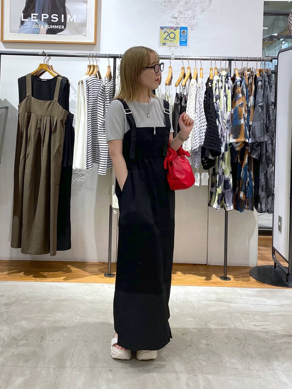 ホワイト系のサンダル、レッド系のショルダーバッグ、ブラック系のジャンパースカートを着用したレディースの夏コーディネートの2枚目の写真