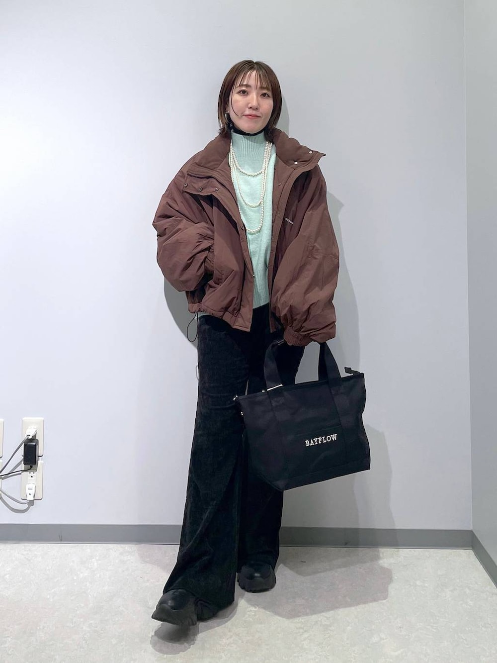 ブラウン系のその他アウター、グリーン系のニット/セーター、ブラック系のその他パンツを着用したレディースの冬コーディネートの3枚目の写真