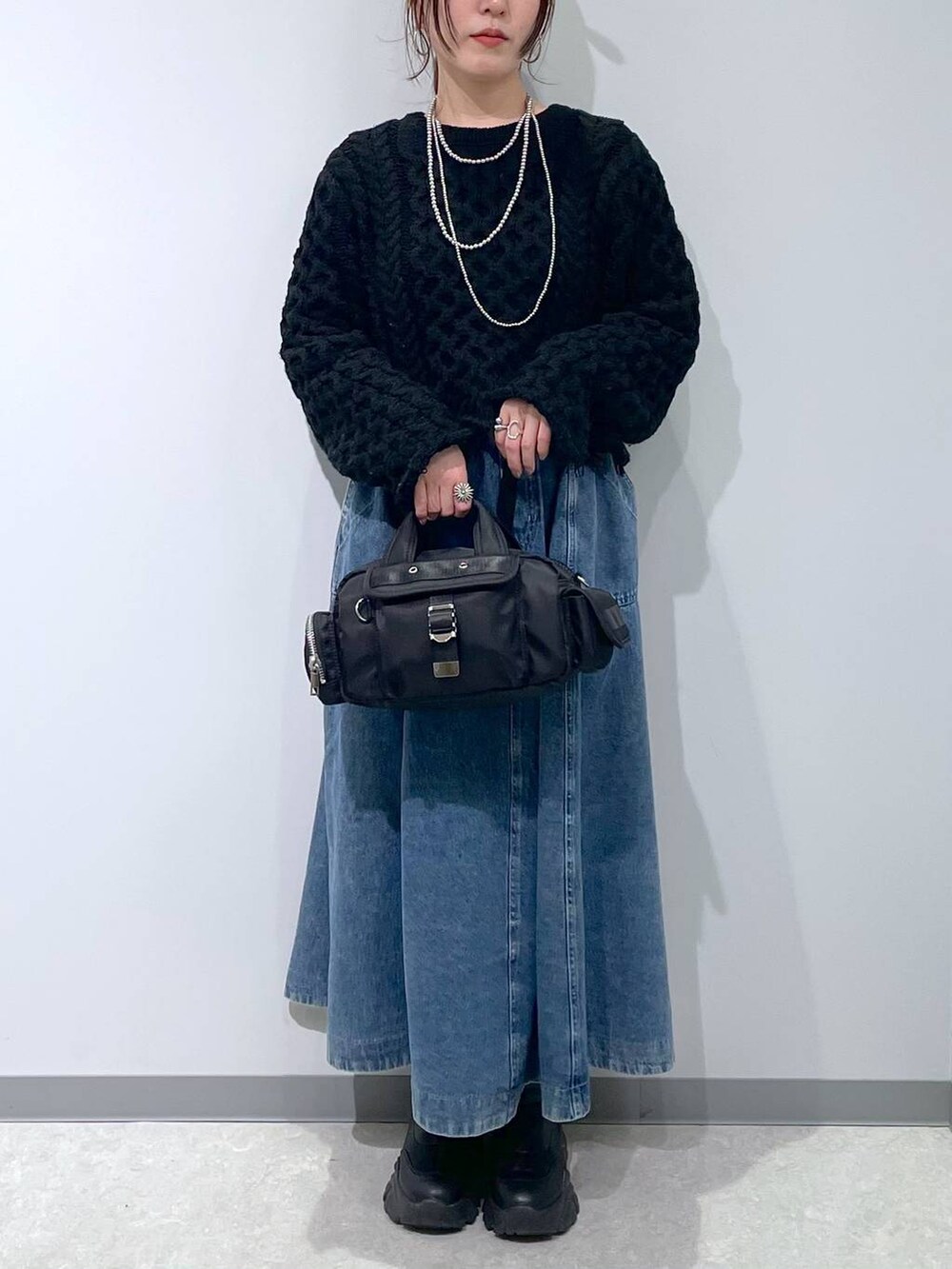 ブラック系のスカート、ブラック系のボストンバッグ、ブラック系のキャップを着用したレディースの冬コーディネートの3枚目の写真