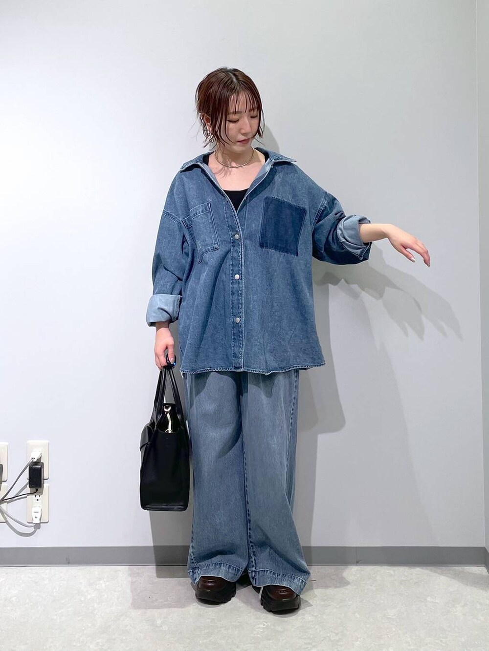 ブルー系のデニムパンツ、ブラック系のハンドバッグ、ブラウン系のローファーを着用したレディースの冬コーディネートの5枚目の写真