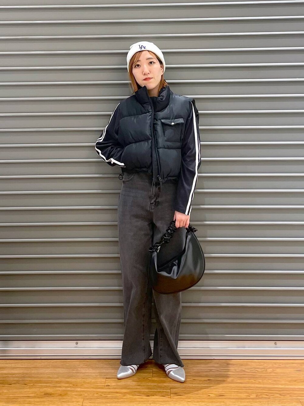 ブラック系のショルダーバッグ、ブラック系のベスト、ブラック系のデニムパンツを着用したレディースの春コーディネートの2枚目の写真