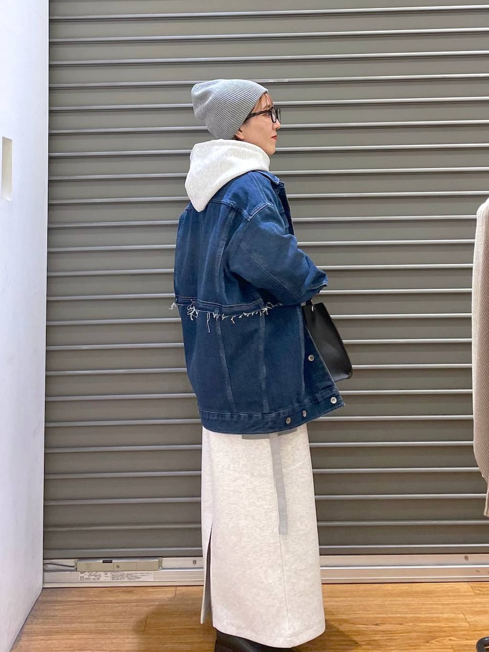 ブルー系のデニムジャケット、グレー系のスカート、ブラック系のショルダーバッグを着用したレディースの冬コーディネートの2枚目の写真