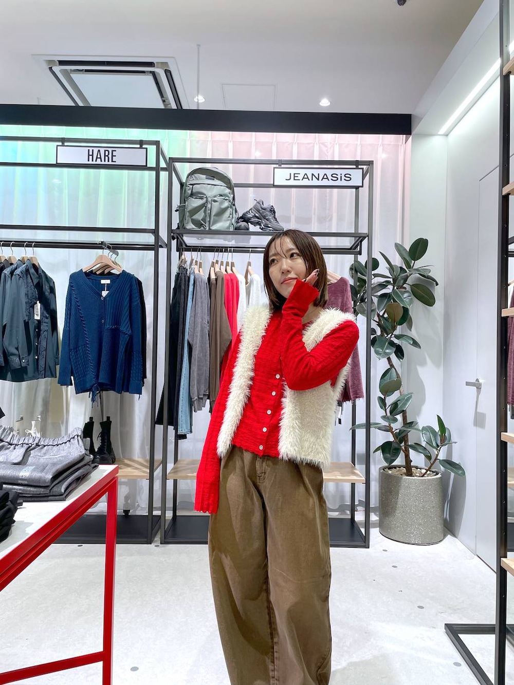 ホワイト系のベスト、ブラウン系のデニムパンツ、レッド系のカーディガン/ボレロを着用したレディースの秋コーディネートの3枚目の写真