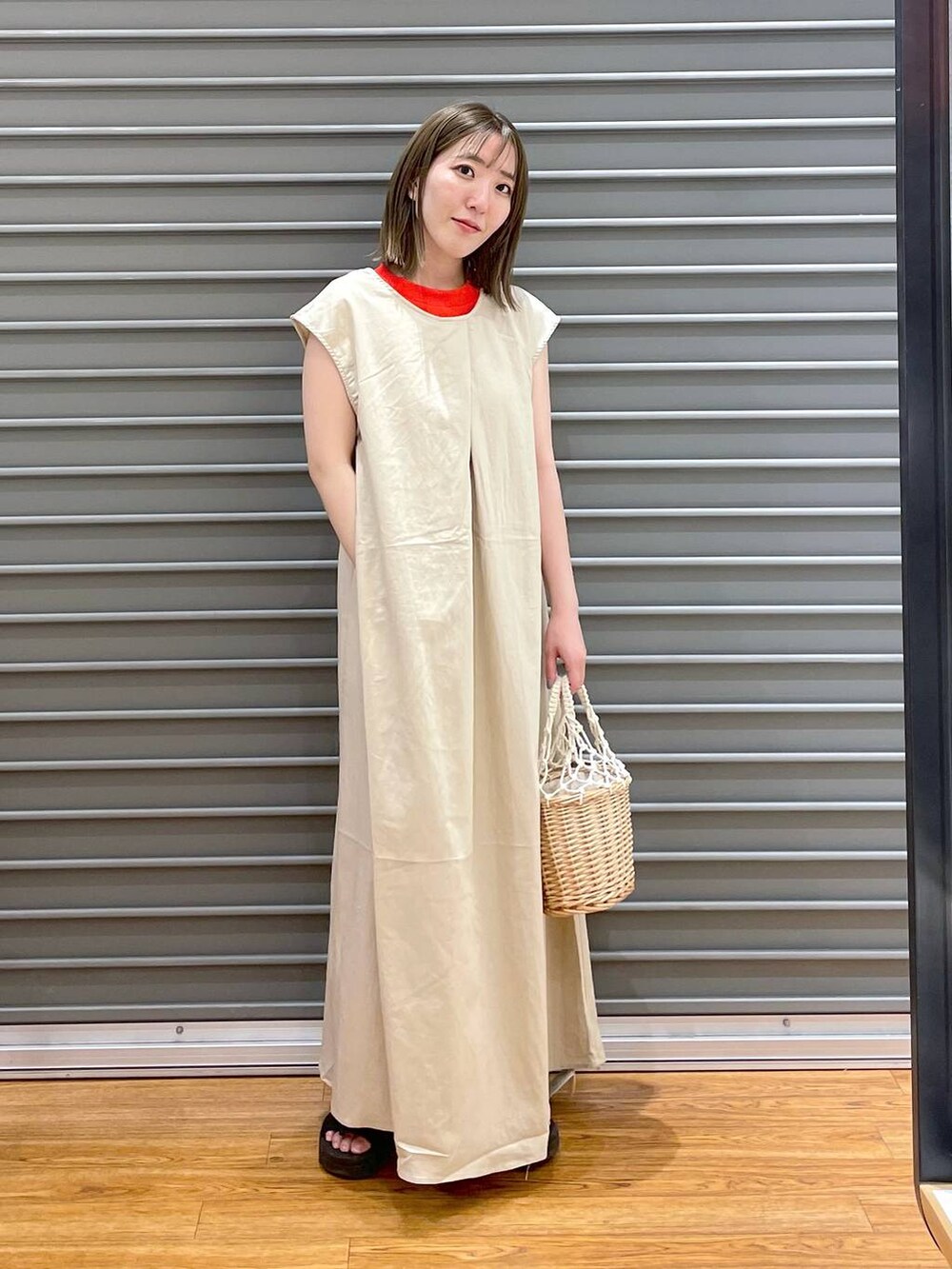 オレンジ系のタンクトップ、ホワイト系のかごバッグ、ホワイト系のワンピースを着用したレディースの夏コーディネートの2枚目の写真