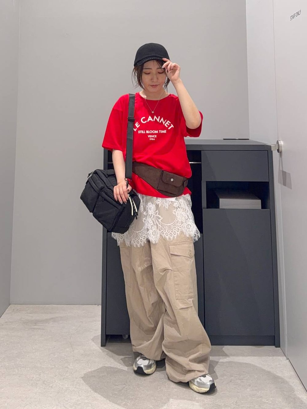 ベージュ系のカーゴパンツ、ブラック系のボストンバッグ、レッド系のTシャツ/カットソーを着用したレディースの夏コーディネートの2枚目の写真