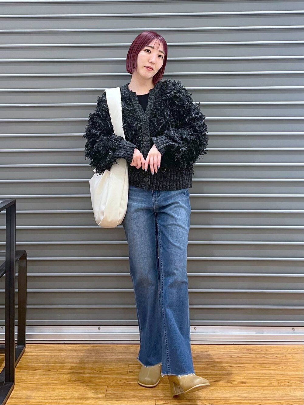 ブルー系のデニムパンツ、ホワイト系のショルダーバッグ、ブラウン系のブーツを着用したレディースの冬コーディネートの2枚目の写真