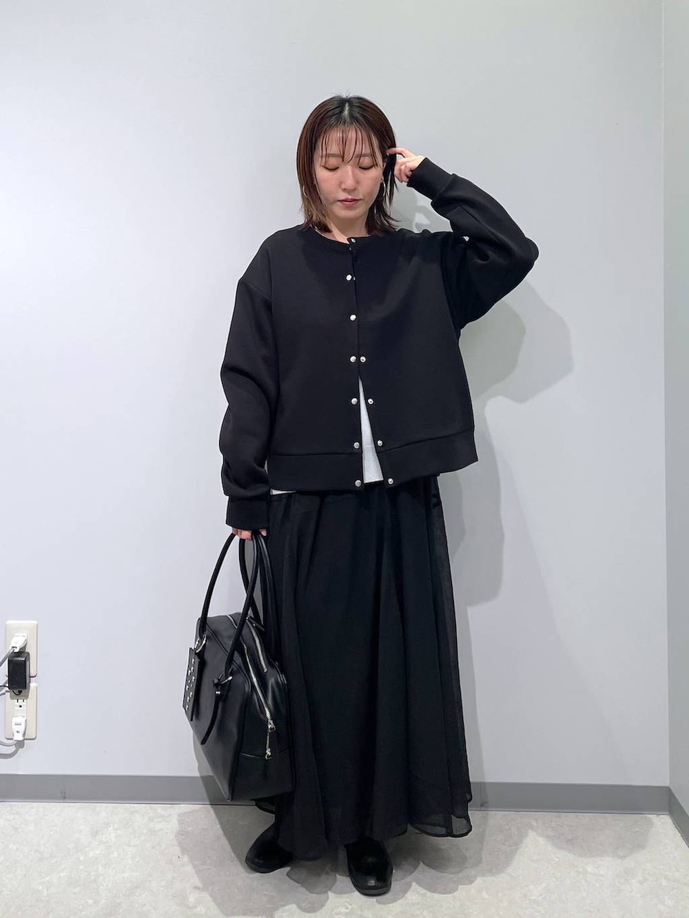 グレー系のニット/セーター、ブラック系のカーディガン/ボレロ、ブラック系のボストンバッグを着用したレディースの春コーディネートの4枚目の写真