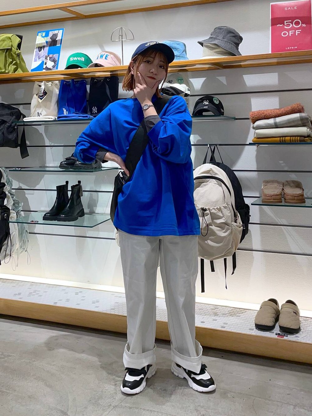 ブラック系のショルダーバッグ、ブルー系のTシャツ/カットソー、ホワイト系のスニーカーを着用したレディースの春コーディネートの3枚目の写真