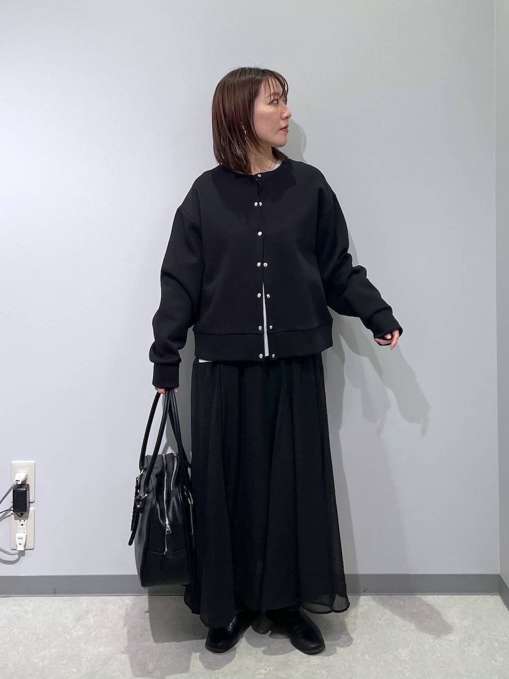 グレー系のニット/セーター、ブラック系のカーディガン/ボレロ、ブラック系のボストンバッグを着用したレディースの春コーディネートの5枚目の写真