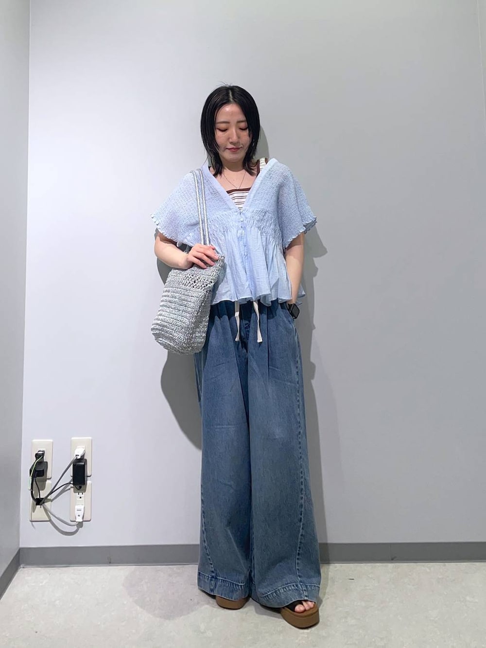 ブラック系のサンダル、ブルー系のデニムパンツ、ホワイト系のタンクトップを着用したレディースの春コーディネートの2枚目の写真