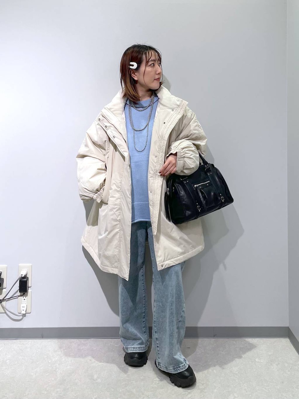 ホワイト系のブルゾン、ブラック系のボストンバッグ、ブルー系のデニムパンツを着用したレディースの冬コーディネートの3枚目の写真