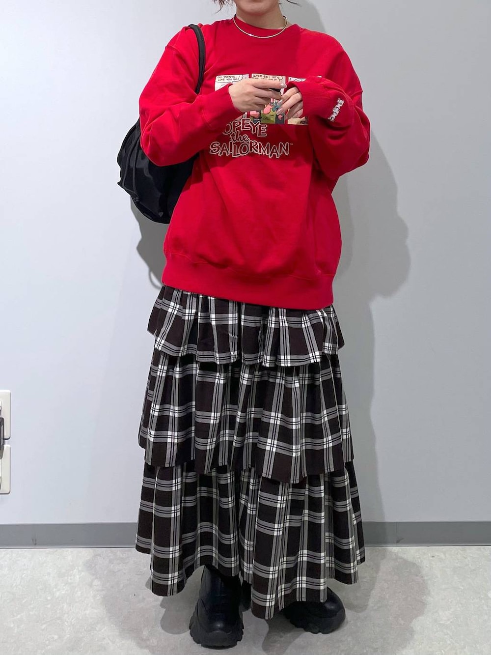 ブラック系のショルダーバッグ、ホワイト系のスカート、レッド系のスウェットを着用したレディースの冬コーディネートの3枚目の写真