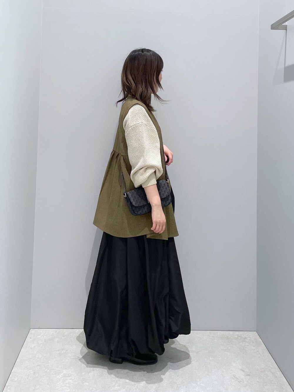 ホワイト系のニット/セーター、ブラウン系のベスト、ブラック系のショルダーバッグを着用したレディースの春コーディネートの2枚目の写真