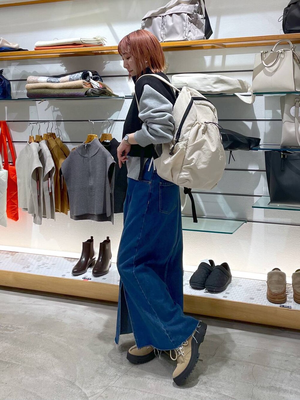 ブラック系のニット/セーター、ベージュ系のブーツ、ホワイト系のバックパック/リュックを着用したレディースの冬コーディネートの2枚目の写真