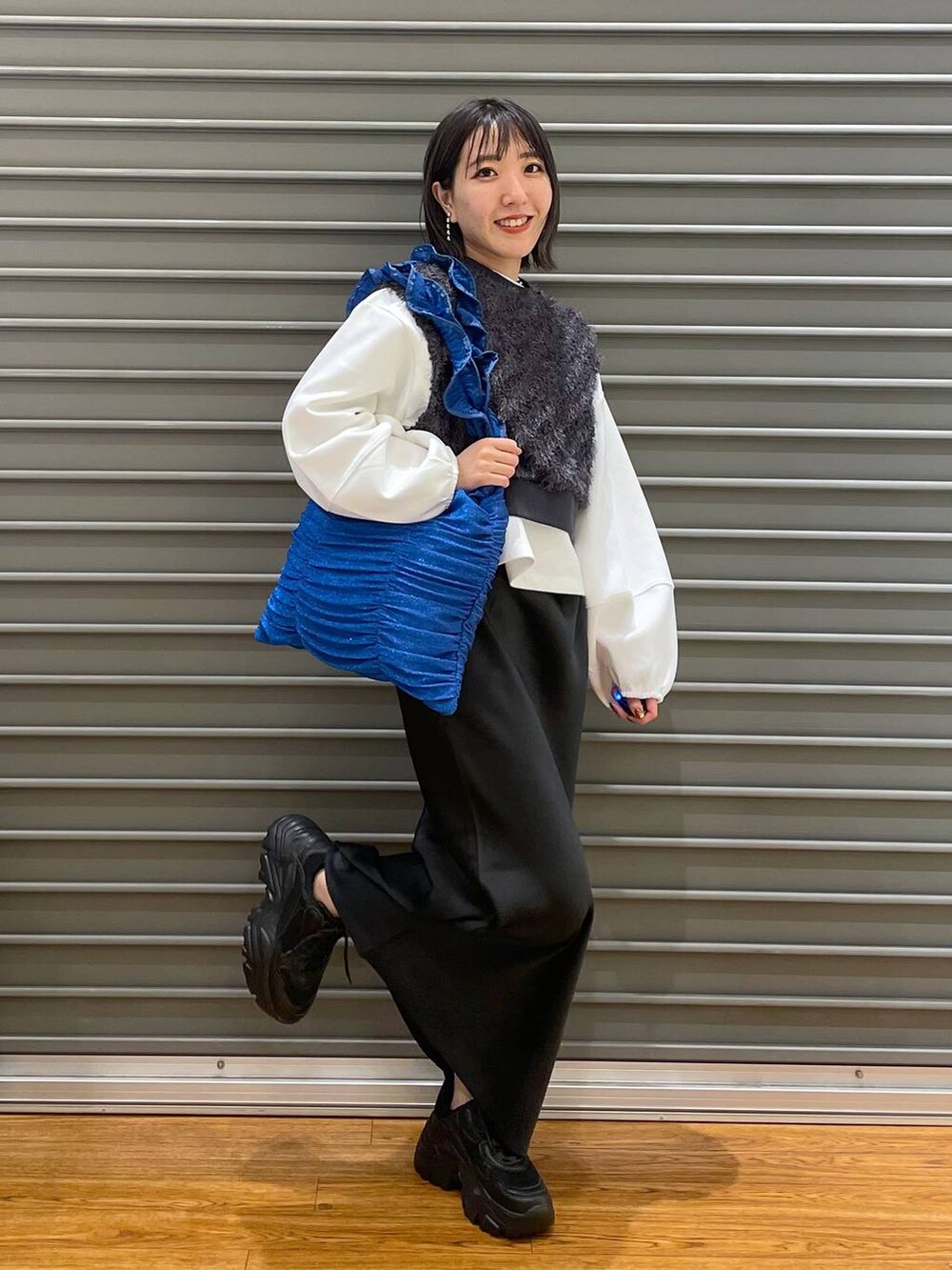 グレー系のベスト、ブラック系のスカート、ホワイト系のTシャツ/カットソーを着用したレディースの春コーディネートの2枚目の写真