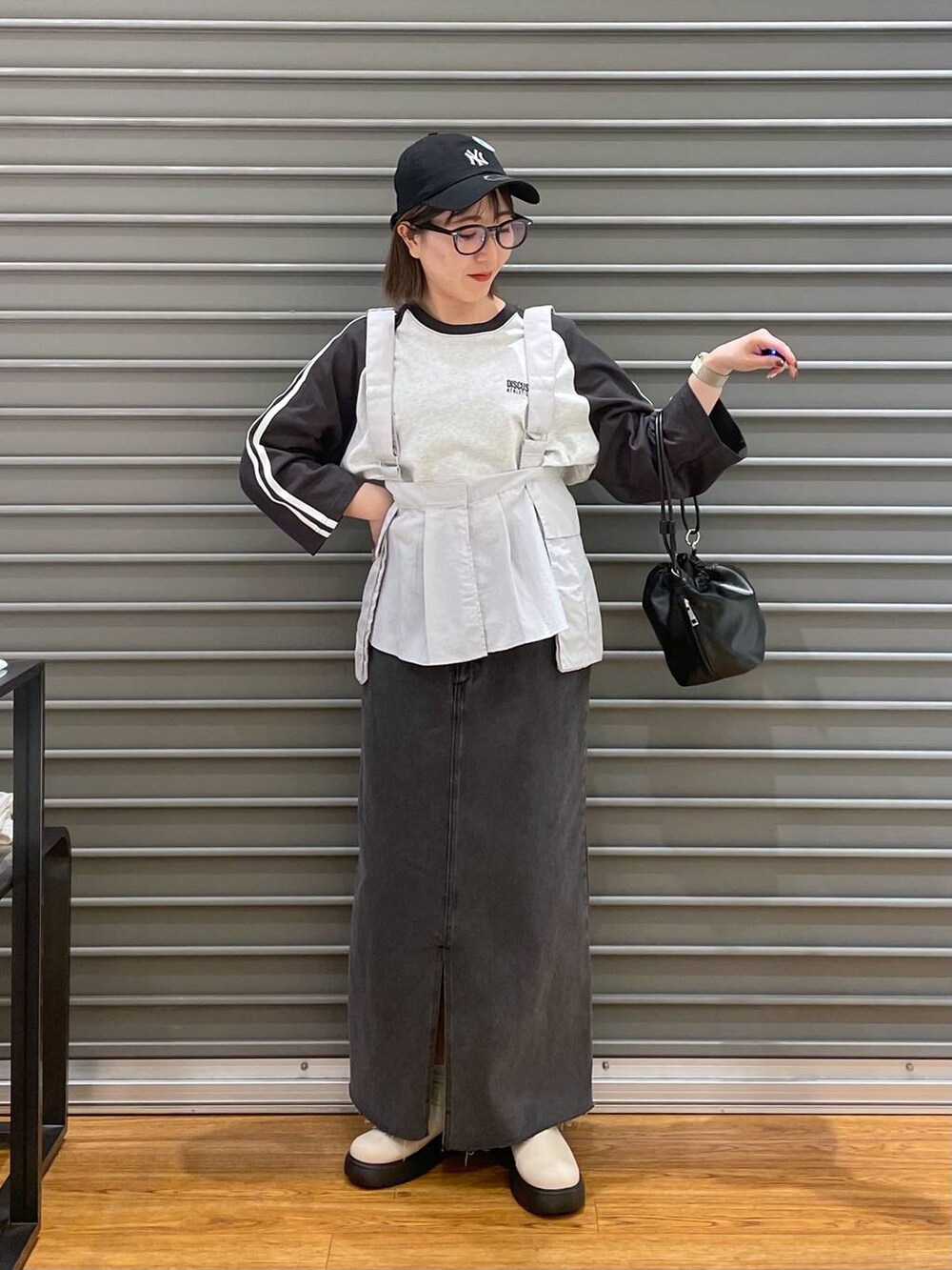 ブラック系のショルダーバッグ、ブラック系のTシャツ/カットソー、ブラック系のスカートを着用したレディースの春コーディネートの2枚目の写真
