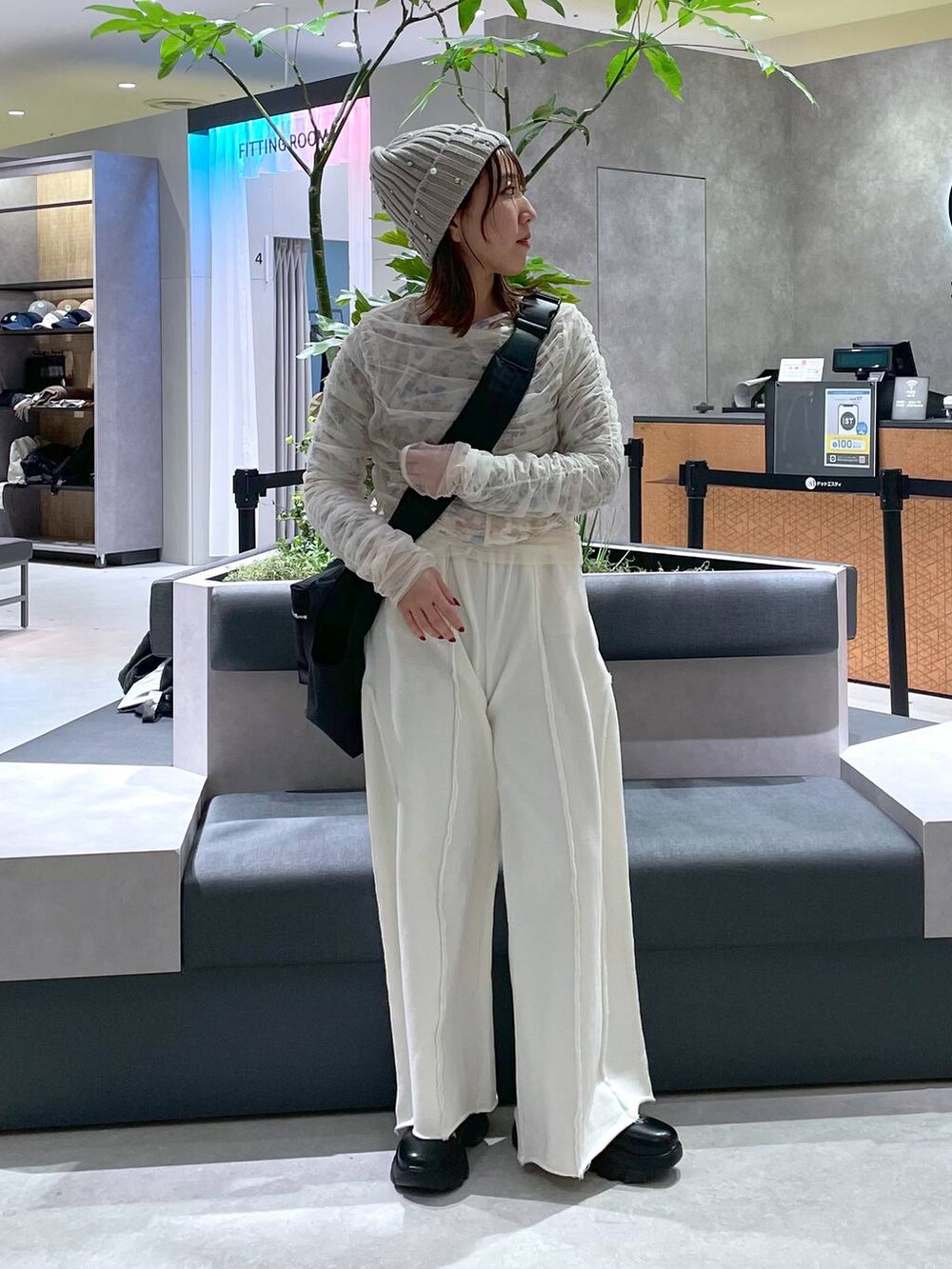 ブラック系のショルダーバッグ、ブラック系のブーツ、ホワイト系のスウェットパンツを着用したレディースの冬コーディネートの4枚目の写真