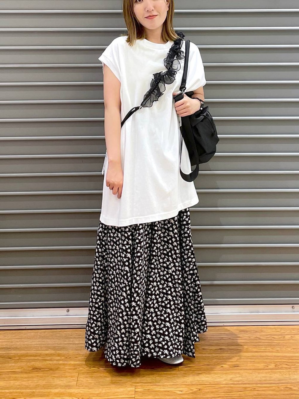 ブラック系のショルダーバッグ、ホワイト系のTシャツ/カットソー、シルバー系のパンプスを着用したレディースの夏コーディネートの2枚目の写真