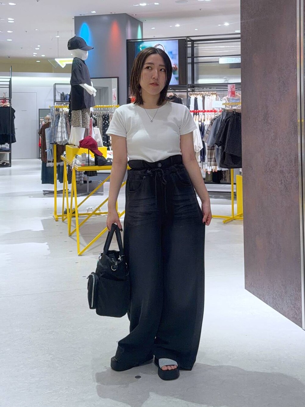 ブラック系のデニムパンツ、ブラック系のトートバッグ、シルバー系のサンダルを着用したレディースの夏コーディネートの2枚目の写真