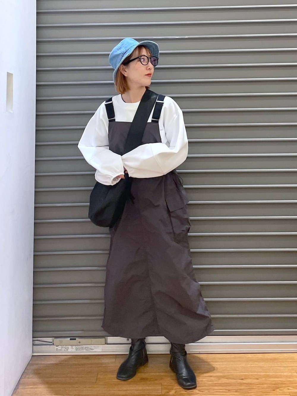 ブラック系のショルダーバッグ、ホワイト系のTシャツ/カットソー、グレー系のジャンパースカートを着用したレディースの春コーディネートの3枚目の写真